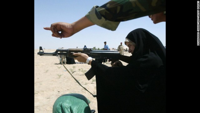 An Iraqi policewoman receives guidance firing an AK-47 during target practice in Karbala, Iraq, in 2008.