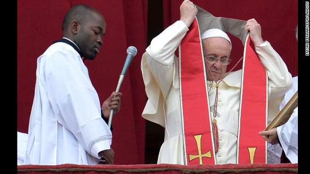 The Pope puts on his sash. The Urbi et Orbi address is customarily political and global, as its name indicates. It is Latin and means "to the city (of Rome) and to the world." Popes give the address and blessing on special occasions such as Easter and Christmas. 