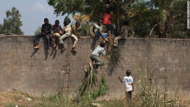 Displaced young people use a tree branch to climb a wall in Bangui on Saturday, December 28.