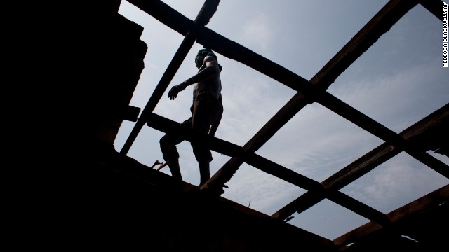 A man walks on a roof beam in Bangui on December 28 as local residents tear apart a house said to have belonged to a Seleka officer who had been attacking the surrounding Christian population.