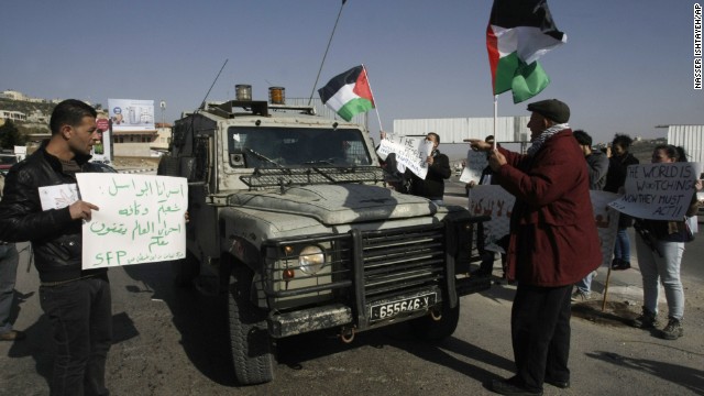 Palestinians raise national flags and hold posters to show their support for prisoners held in Israeli jails on December 28.