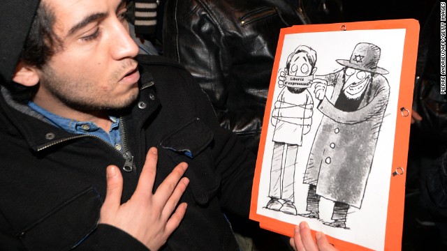 Supporters of Dieudonne argue that the issue of "freedom of speech" in France is at stake after Valls called for the comic's performances to be banned. Here a man poses with one of his drawings showing a Jewish character covering the mouth of another character with a gag reading "freedom of speech."