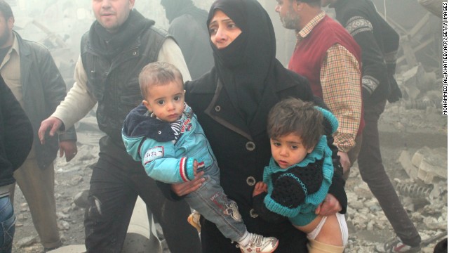 A Syrian woman carries children following airstrikes on Aleppo on December 15.