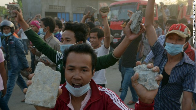 Cambodian garment workers carry rocks as they shout slogans after a brief clash with police during a protest to demand higher wages in front of a factory in Phnom Penh on January 2.