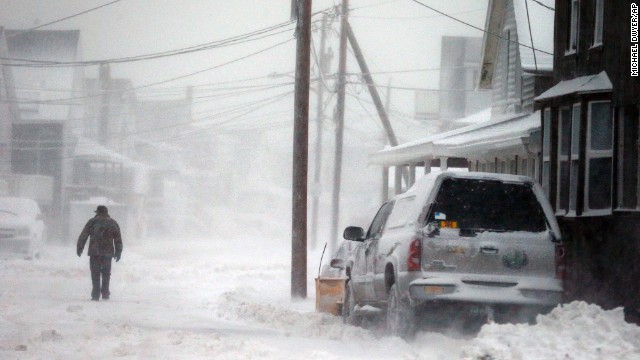 A man walks down a snowy road along the shore in Scituate, Massachusetts, on Friday, January 3.