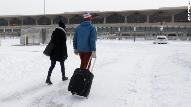 A couple walks across a snow-covered parking lot January 3 at Newark Liberty International Airport. 