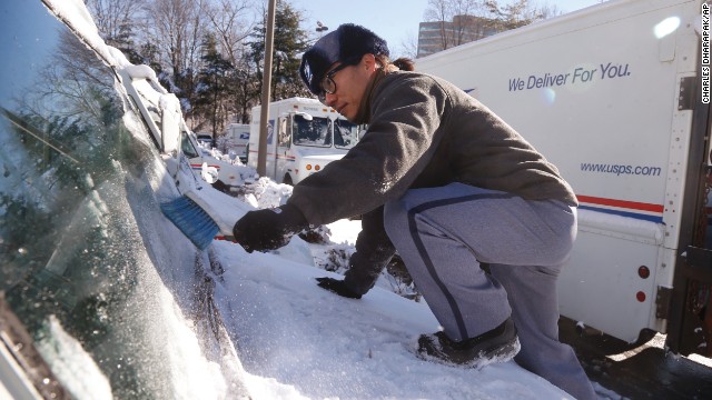 Postal worker Danny Kim clears snow and ice off the hood of his delivery truck January 3 in Bethesda, Maryland.