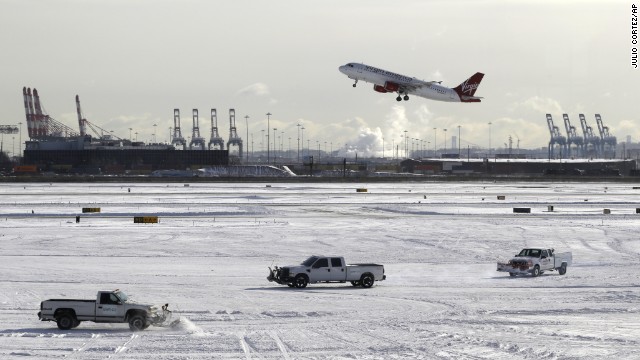 A plane takes off January 3 as trucks plow snow at Newark Liberty International Airport in Newark, New Jersey.