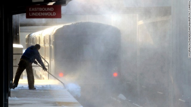 Blowing snow swirls as a worker shovels a platform at a Haddonfield, New Jersey, train station on January 3.