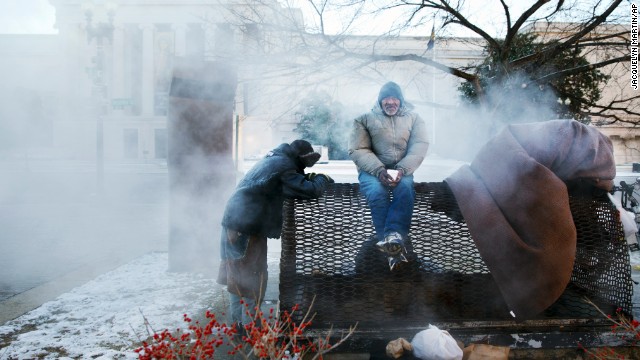 Four homeless men warm themselves on a steam grate by the Federal Trade Commission Building, blocks from the U.S. Capitol in Washington, as frigid temperatures grip the nation's capital on Saturday, January 4.