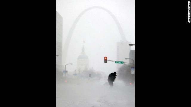 With the Gateway Arch in the distance, a person struggles to cross the street during a snowstorm January 5 in downtown St. Louis.