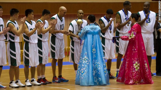 Christie is handed a trophy as North Korean players applaud at the end of the game.