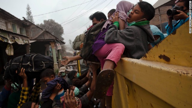 A man helps children onto a truck as residents are evacuated.