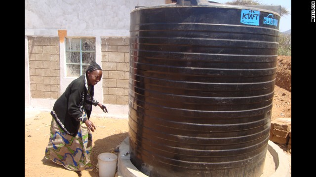 A woman draws water from a collection tank. Borrowers in Kenya are using WaterCredit loans to purchase large water storage tanks. These water tanks provide additional income to families, who sell the water to neighbors or irrigate gardens and fields for better crops.