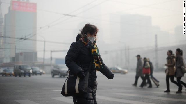 A woman wears a face mask on January 16 as thick smog cuts visibility in the Chinese capital. China has seen a huge increase in coal-burning power plants, and its manufacturing practices aren't nearly as efficient as in the West.