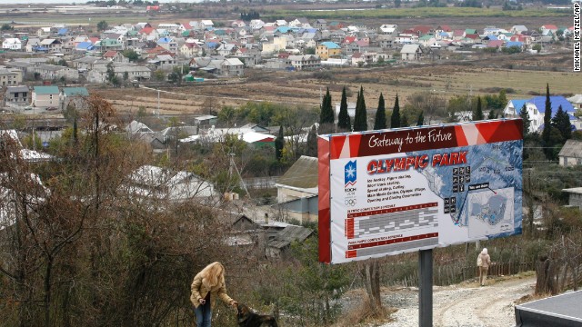 In the Imeretinskay Valley, a woman plays with a dog in February 2007, near an advertisement for the Olympic Park soon to be built in the area. Organizers of the Sochi Olympics say they want these Games to be the greenest, most environmentally aware games ever staged. 