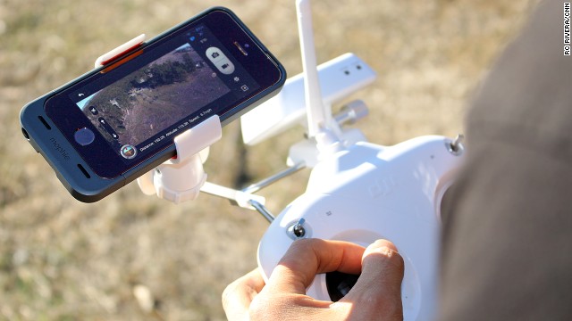 Live video from a DJI Phantom drone is displayed on an iPhone app. The Phantom controller has a special mount for the smartphone. 