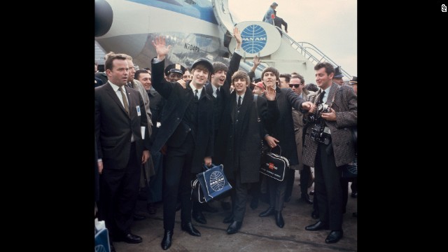 The band waves to cameras at John F. Kennedy International Airport.