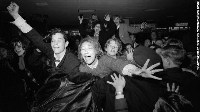 Beatles fans are restrained by police at the airport.