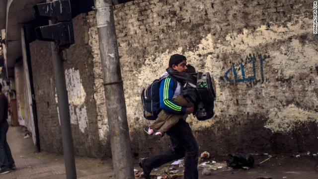 A man carries his son to escape clashes between police and anti-military protesters.