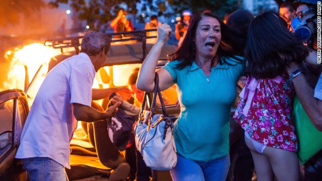 People help a family out of a burning car in Sao Paulo last January after it drove over a barricade of fire started by protesters, during demonstrations against the staging of the World Cup.