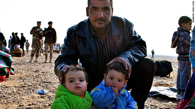 A father poses with his twins near the Jordanian border. The man told CNN he came across the border with about 10 other members of his family from the Damascus suburbs.