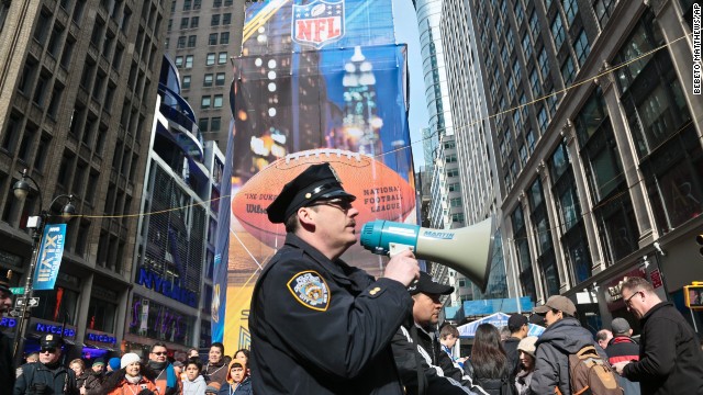 A New York City police officer use a bull horn to direct pedestrians visiting Super Bowl Boulevard on February 1 in New York.