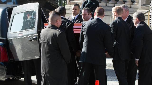 Pallbearers lift Hoffman's casket into the back of a hearse.