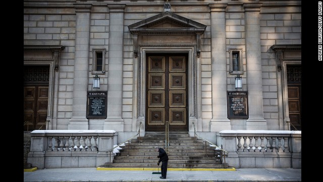 A man cleans the steps of the church.