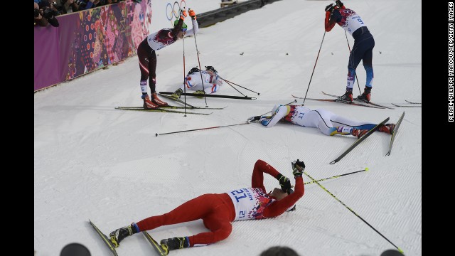 Swiss skier Dario Cologna, foreground, lies on the snow alongside other competitors in the men's skiathlon.