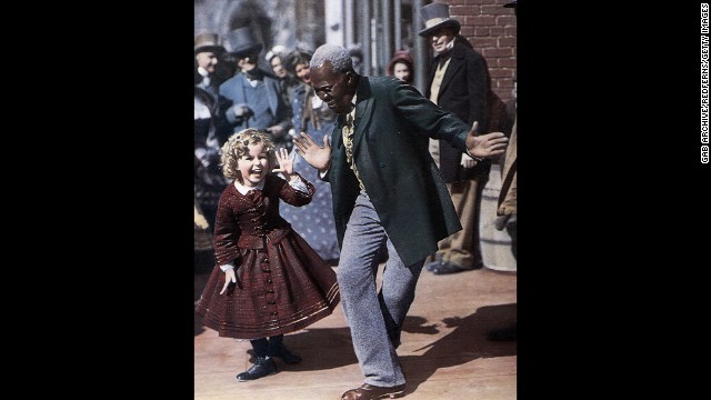Billy "Bojangles" Robinson and Shirley Temple dance together on set in 1935.