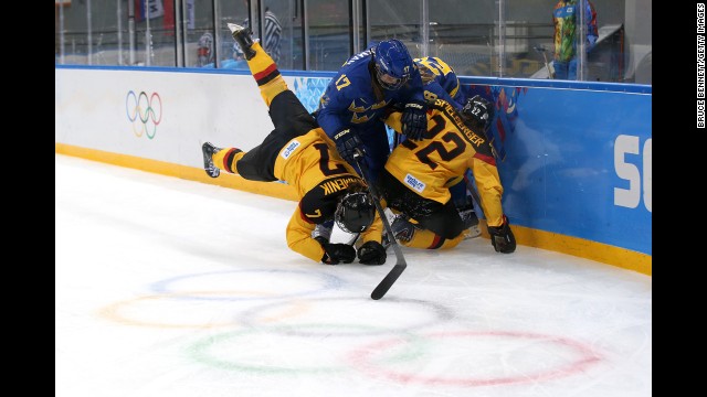 Linnea Backman of Sweden, center, fights for the puck against Nina Kamenik, left, and Kerstin Spielberger of Germany during their Group B hockey game on February 11.
