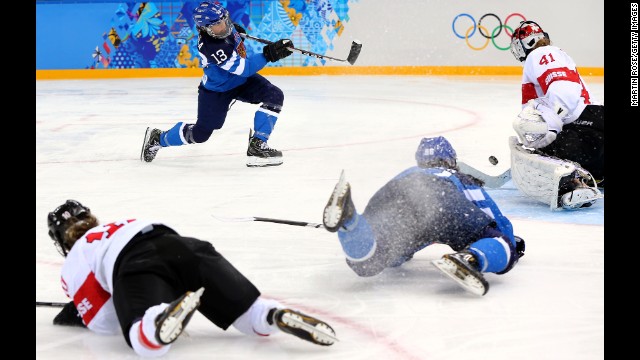Riikka Valila of Finland takes a shot against Florence Schelling of Switzerland while teammates crash on the ice during a women's hockey game February 12.