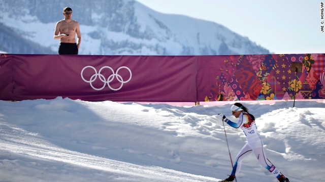 A shirtless spectator watches Swedish cross-country skier Charlotte Kalla compete during the women's 10-kilometer classic on February 13.