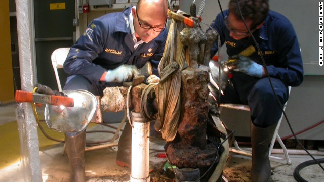 Paul Mardikian, left, senior conservator, and Philippe de Vivies remove material from a piece of the submarine.