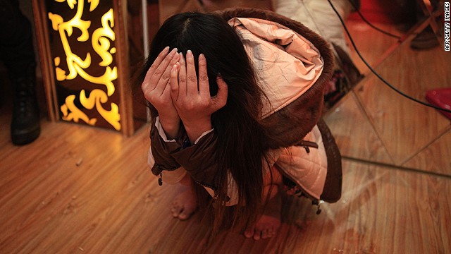 An alleged sex worker covers her face after being detained in Dongguan, China, on February 9, 2014
