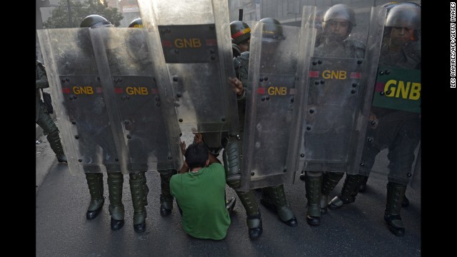A student falls to the ground in front of riot police in Caracas on February 12.