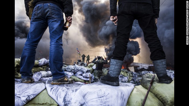 Protesters watch clashes in Kiev on February 18.