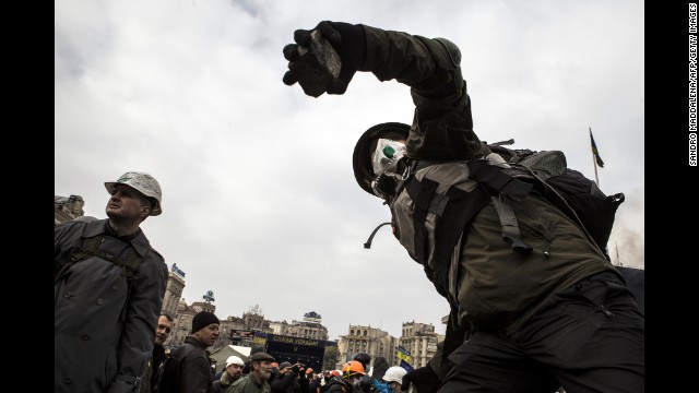 A protester throws a cobblestone at riot police during clashes in Independence Square on February 19.