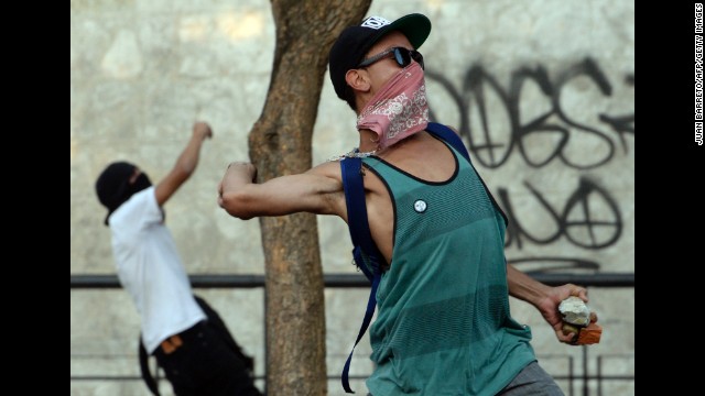 Protesters throw stones at riot police in Caracas on February 19. Protesters have been demanding better security, an end to scarcities, and protected freedom of speech.