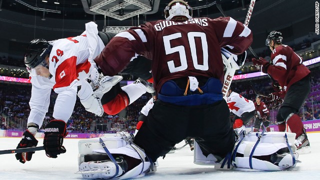 Canada forward Corey Perry trips over Latvia goaltender Kristers Gudlevskis during the men's ice hockey quarterfinal on Wednesday, February 19.