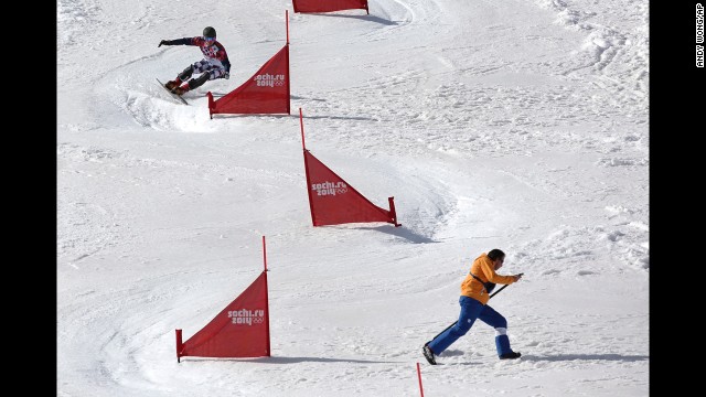 Russia's Vic Wild takes a turn as a course worker runs to get out of the way during a the snowboard parallel slalom quarterfinal on February 22.