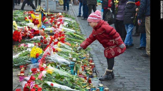 KIEV, UKRAINE: A young girl pays tribute to anti-government protesters killed in the clashes with riot police by placing a flower on a makeshift memorial leading to the barricades in central Kiev on February 24. Photo by CNN's Todd Baxter.