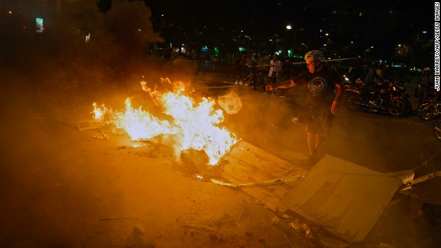 A man stands next to a burning street barricade during a protest against the Venezuelan government in Caracas on Monday, February 24.
