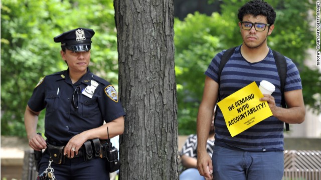 An NYPD officer and a protester look on as advocates and residents hold a press conference June 18, 2013, in New York to discuss legal action challenging surveillance of businesses frequented by Muslim residents and of mosques. 