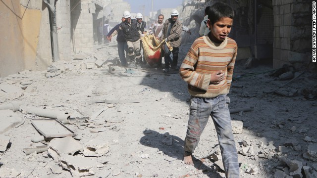 A boy walks ahead of men carrying the body of his mother in Aleppo, Syria, on Saturday, February 22. According to activists, the woman was killed when explosive barrels were thrown by forces loyal to Syrian President Bashar al-Assad.