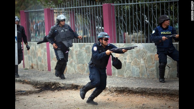 A policeman fires his shotgun to disperse protesters in Valencia on February 26.