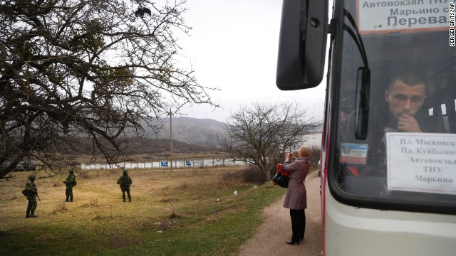 A woman photographs pro-Russian soldiers guarding Ukraine's infantry base in Perevalne on March 4.