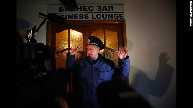 A Ukrainian police officer gives instructions to members of the media in front of the business class lounge of the Simferopol airport on March 5.