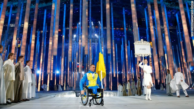 Biathlete Mykhaylo Tkachenko carries the Ukrainian flag into the stadium.